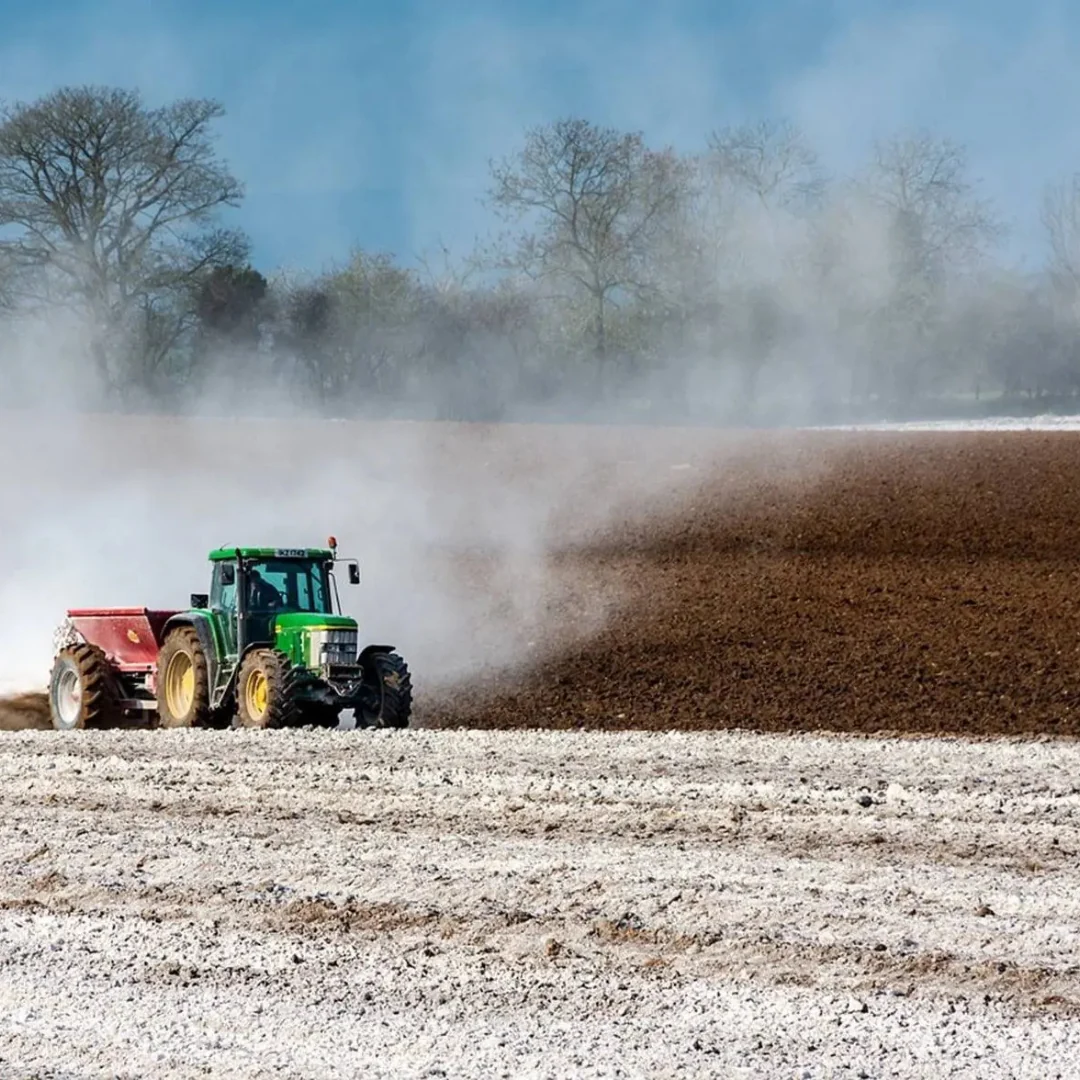 Trator realizando aplicação de calcário agrícola no campo